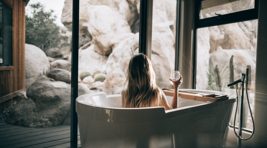 woman in white bathtub holding clear drinking glass