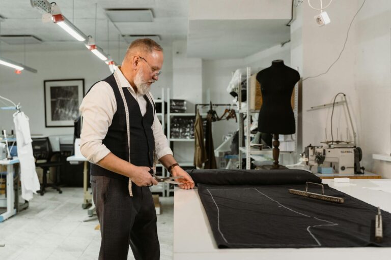 Elderly tailor meticulously creating custom garments in a contemporary workshop.